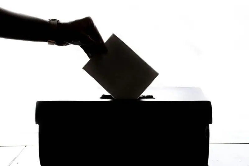 Silhouette of a hand placing a ballot in a box